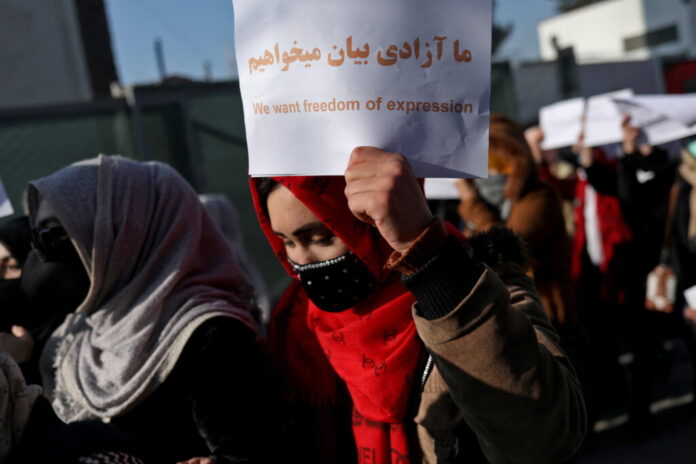 Afghan woman holds up a placard during a rally to protest against what the protesters say is Taliban restrictions on women, in Kabul